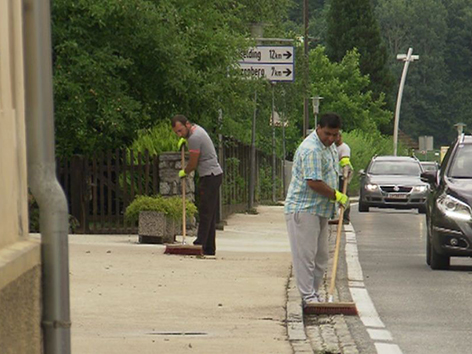 Flüchtlinge arbeiten bei der Straßenreinigung