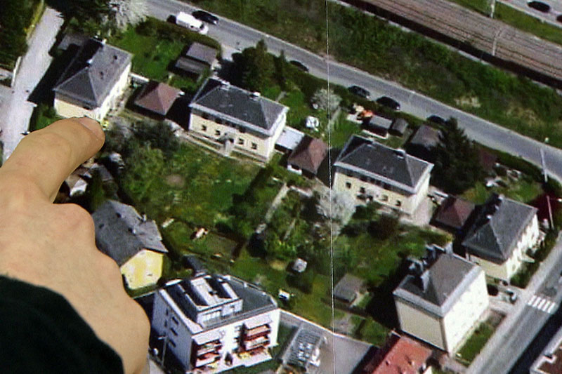 Finger zeigt auf Luftbild von alten Wohnhäusern in Salzburg Itzling
