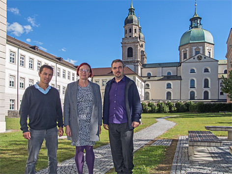 © ORF/Hammer Drei Menschen im Garten vor Universität und Kirche