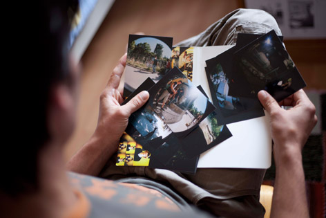 © © Ida Kielmansegg Sharukh sucht Fotos aus, Blick von oben auf die Fotos in seinem Schoß