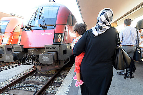 © APA/Roland Schlager Frau mit Kind am Arm neben einer Lok